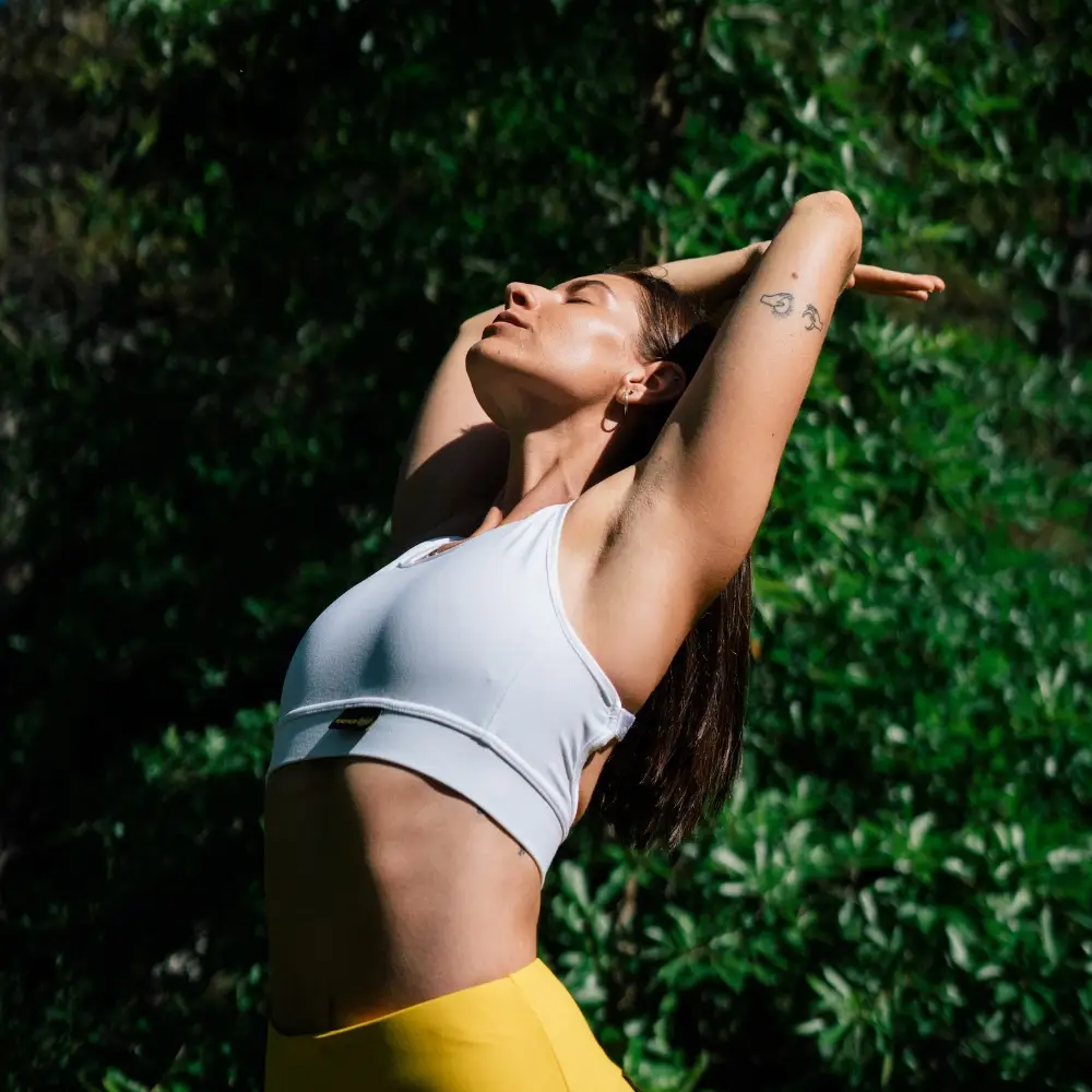 Young girl stretching her back with arms raised behind her head, showing healthy, pain-free movement after non-surgical back pain relief.