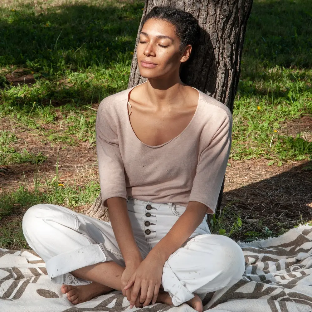 Woman sitting beneath a tree, feeling relaxed and pain-free after receiving compassionate, non-surgical pain relief in Chicago.